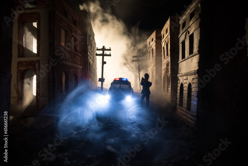 Police raid at night and you are under arrest concept. Silhouette of handcuffs with police car on backside. Image with the flashing red and blue police lights at foggy background. Slider shot