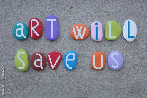 Art will save us, creative quote composed with multi colored stone letters over green sand