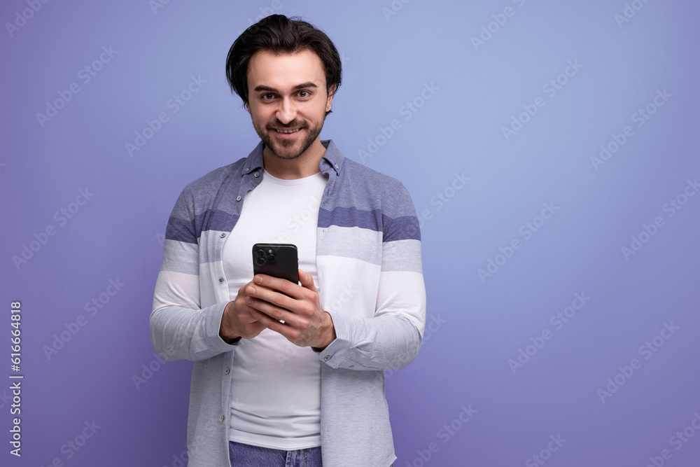 nice brunette guy in casual style communicates using smartphone nice brunette guy in casual style communicates using smartphone