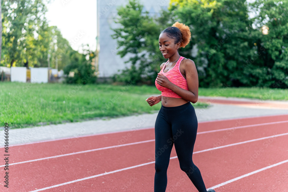 The confident black woman casually jogs on a running track, exuding grace and ease. Her relaxed stride inspires with its effortless beauty, showcasing her love for running The confident black woman casually jogs on a running track, exuding grace and ease. Her relaxed stride inspires with its effortless beauty, showcasing her love for running
