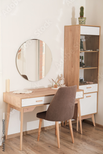 modern interior of bedroom, dressing table with mirror and soft upholstered chair. trendy minimal style decor. vertical shot. 