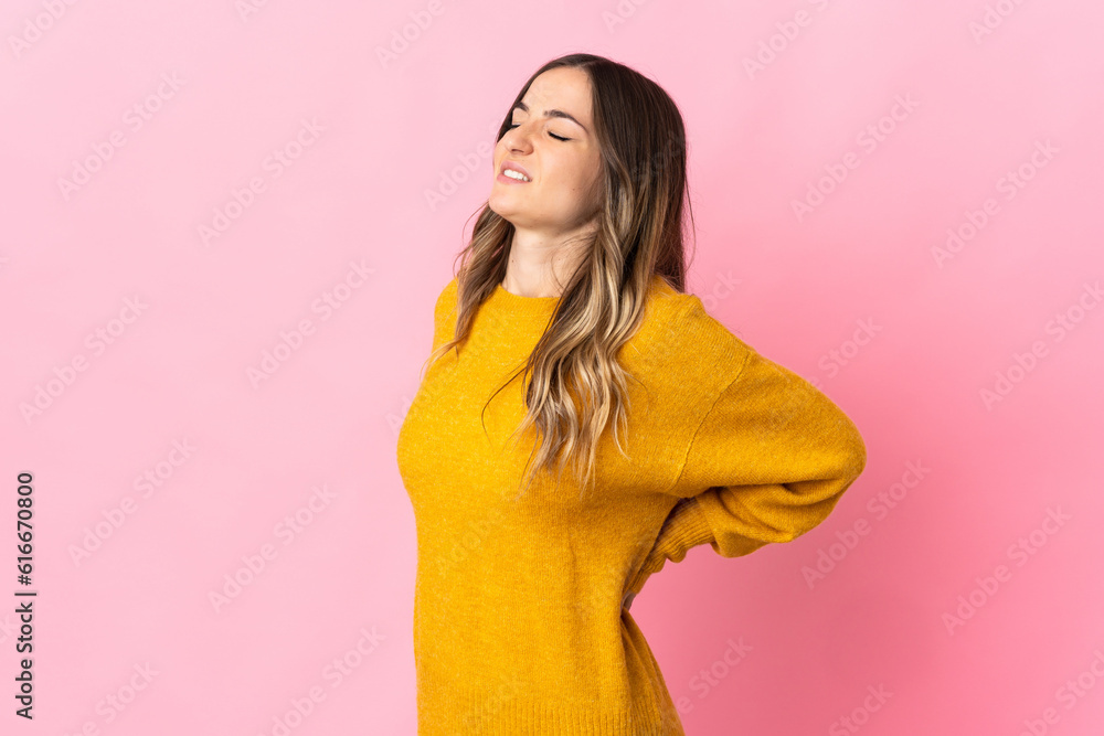 Young Romanian woman isolated on pink background suffering from backache for having made an effort Young Romanian woman isolated on pink background suffering from backache for having made an effort