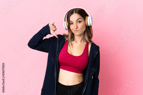 Young Romanian sport woman isolated on pink background showing thumb down with negative expression