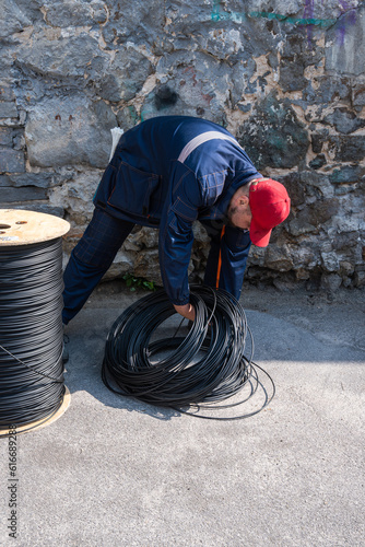 A man picks up a black cable from the ground  fiber optic  coaxial  electrical  ethernet