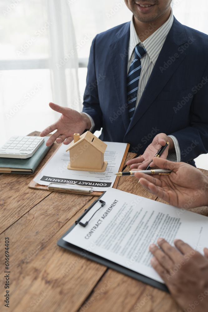 A real estate agent is explaining model house plans and agreeing on a house price. before delivering the house to the customer Mortgage, purchase and home insurance concepts. A real estate agent is explaining model house plans and agreeing on a house price. before delivering the house to the customer Mortgage, purchase and home insurance concepts.