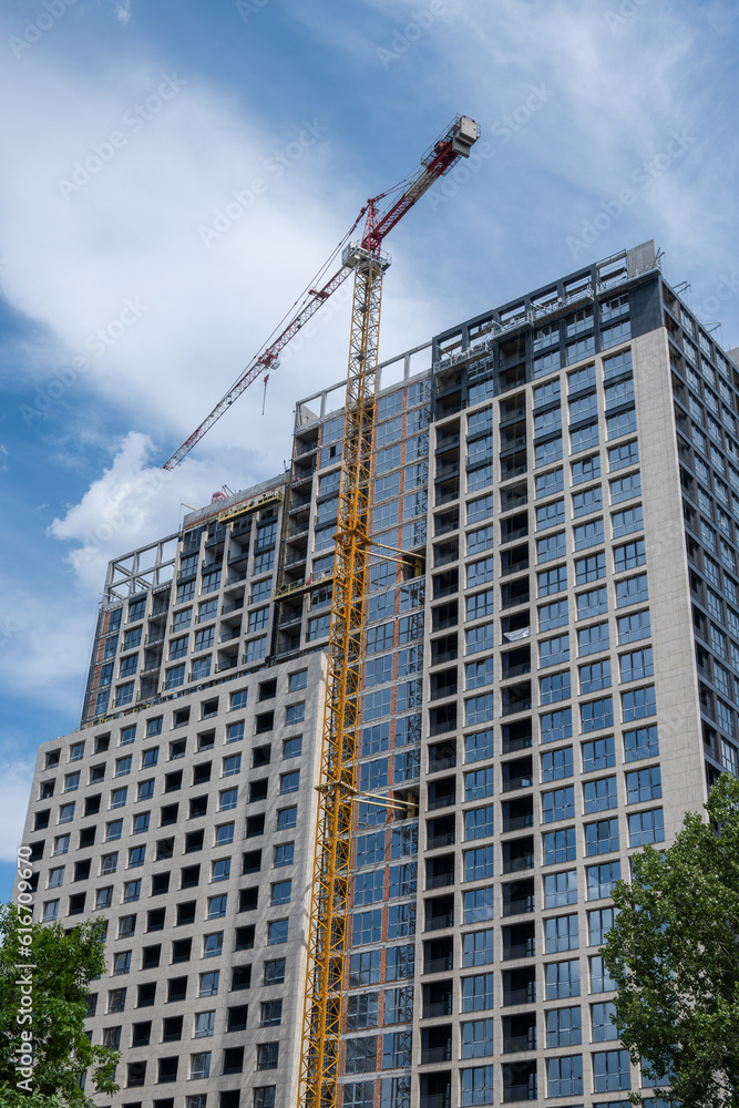 Fototapeta premium Construction site with high-rise crane. Construction of modern apartment buildings and a new residential complex. Bottom up view
