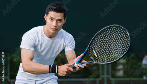 Motivated sportsman in white costume playing tennis on outdoor court. Sport, competition, healthy and active lifestyle concept.