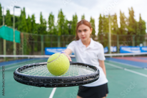 Closeup of female tennis player hand holding racket and ball while playing tennis on a sunny day. © wattana