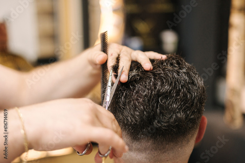 First person view of hairdresser cuts hair using scissors and comb. Professional barber 