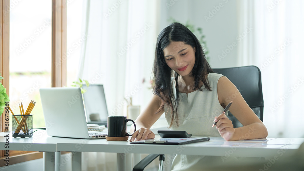 Attractive businesswoman using laptop computer and checking financial reports on white office desk.. Attractive businesswoman using laptop computer and checking financial reports on white office desk..