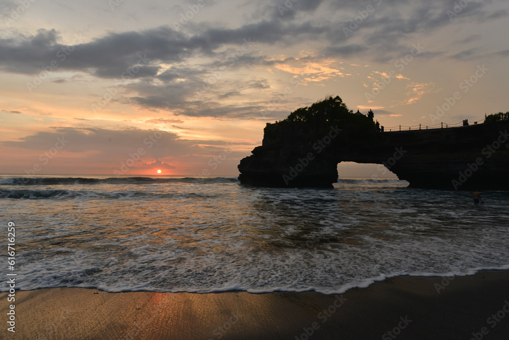 Natural rock cave formation and wave in the sunset at Pura Batu Bolong, Indonesia