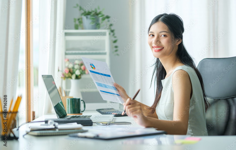 Successful businesswoman holding document and working with computer laptop.
