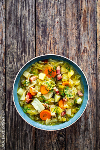 Hot cabbage soup with bacon on wooden table
