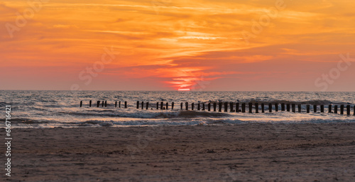 Sunset on Baltic sea shore with old wooden breakwater poles sticking out of the sea in Bernati  Latvia. Long exposure photography.