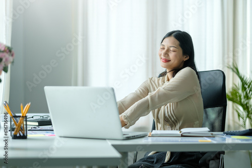 Pretty young woman stretching her arms while relaxing at her workplace.