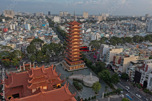 Aerial view of Buddhist pagoda in Ho Chi Minh City  Vietnam. Drone orbits the building in clockwise direction revealing the urban sprawl and rooftops of District ten in clear afternoon light. 