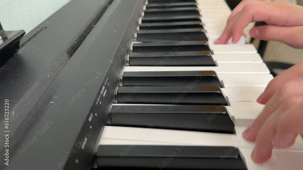 a little girl playing the piano at home, a girl playing a musical instrument, the hands of a child playing the piano close-up.