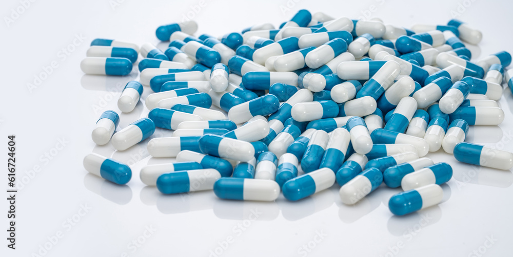 Blue-white antibiotic capsule pills on white background. Pile of antibiotic drug. Antibiotic drug resistance. Prescription drugs. Healthcare and medicine. Pharmaceutical industry. Pharmacy product. Blue-white antibiotic capsule pills on white background. Pile of antibiotic drug. Antibiotic drug resistance. Prescription drugs. Healthcare and medicine. Pharmaceutical industry. Pharmacy product.