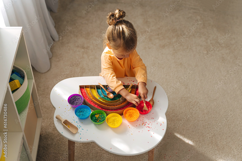 Foto de A little girl playing colored rice and make rainbow. Child ...