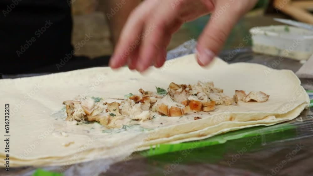 hands spread the stuffing in a pita bread in nature,cooking shawarma on a picnic in summer, outdoor party hands spread the stuffing in a pita bread in nature,cooking shawarma on a picnic in summer, outdoor party