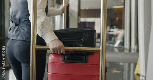 Follow shot of bellman pushing baggage cart along hotel corridor helping customers with luggage working alone. People and job concept.