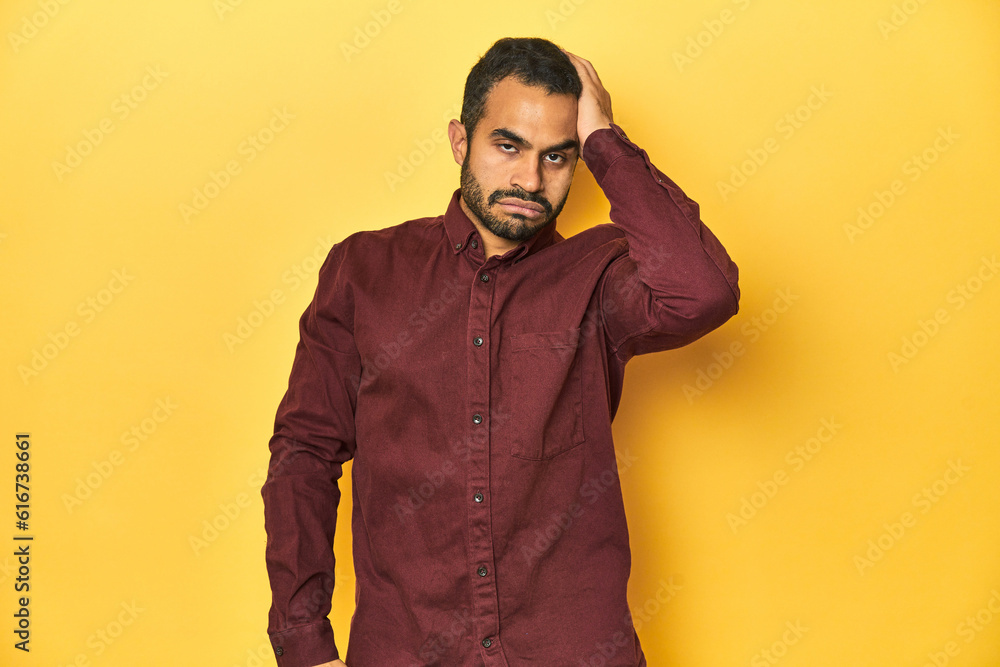 Casual young Latino man against a vibrant yellow studio background, tired and very sleepy keeping hand on head. Casual young Latino man against a vibrant yellow studio background, tired and very sleepy keeping hand on head.