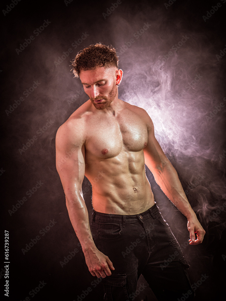 Handsome male bodybuilder in studio shot, looking down to a side