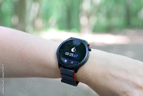 Smart watch on female hand with stopwatch. Round display with app for sports training