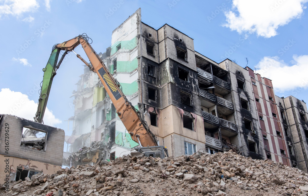 Demolition of a high-rise building. The collapse of a residential building. Construction work on the demolition of multi-storey apartments. Excavator with hydraulic crusher. Demolition of a high-rise building. The collapse of a residential building. Construction work on the demolition of multi-storey apartments. Excavator with hydraulic crusher.