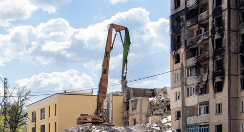 Demolition of a high-rise building. The collapse of a residential building. Construction work on the demolition of multi-storey apartments. Excavator with hydraulic crusher.