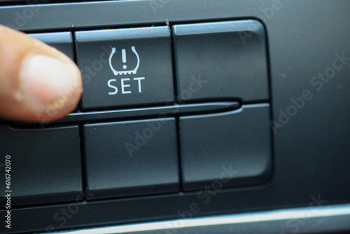 The driver presses the TPMS button to activate the TPMS feature on his car photo