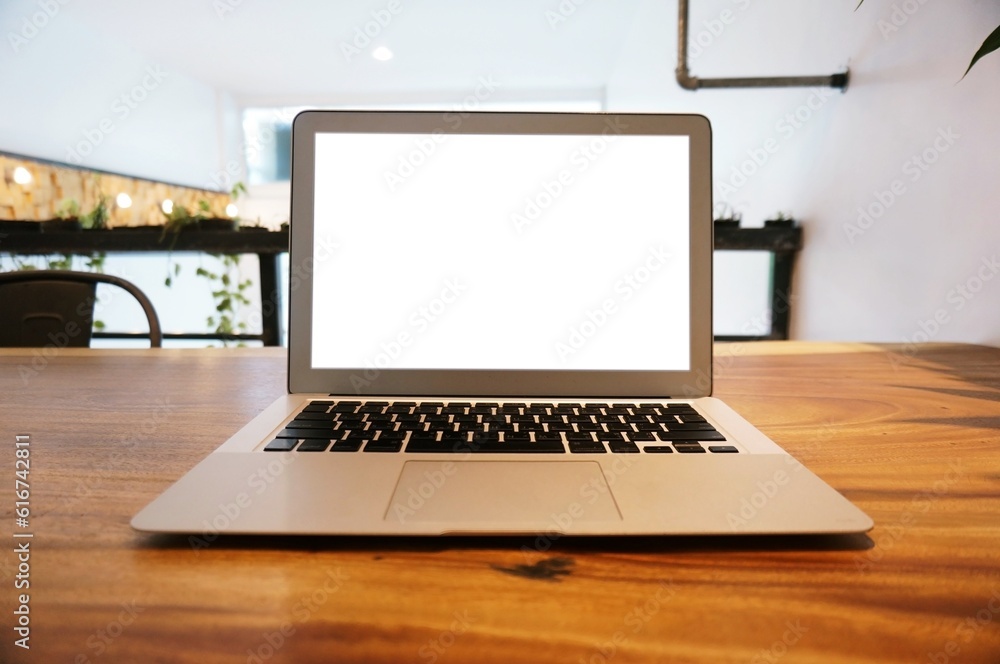 Laptop with Mock up blank screen on wooden table in front of coffeeshop cafe space for text. product display montage- technology concept Laptop with Mock up blank screen on wooden table in front of coffeeshop cafe space for text. product display montage- technology concept