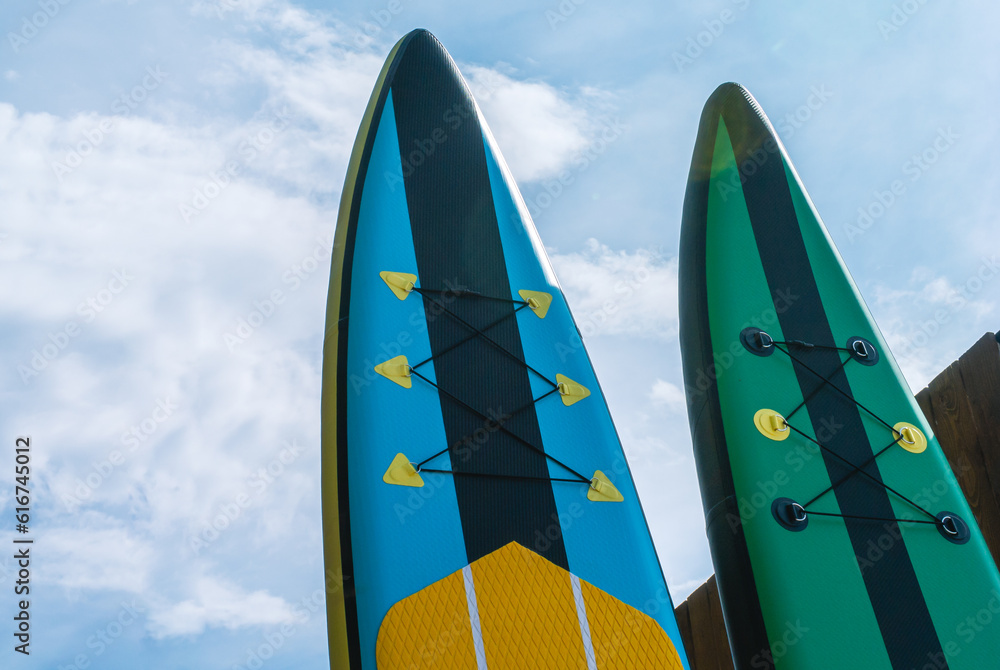 Water sports. Inflatable multicolored sap boards on a background of blue  sky. Tourism on sap boards.