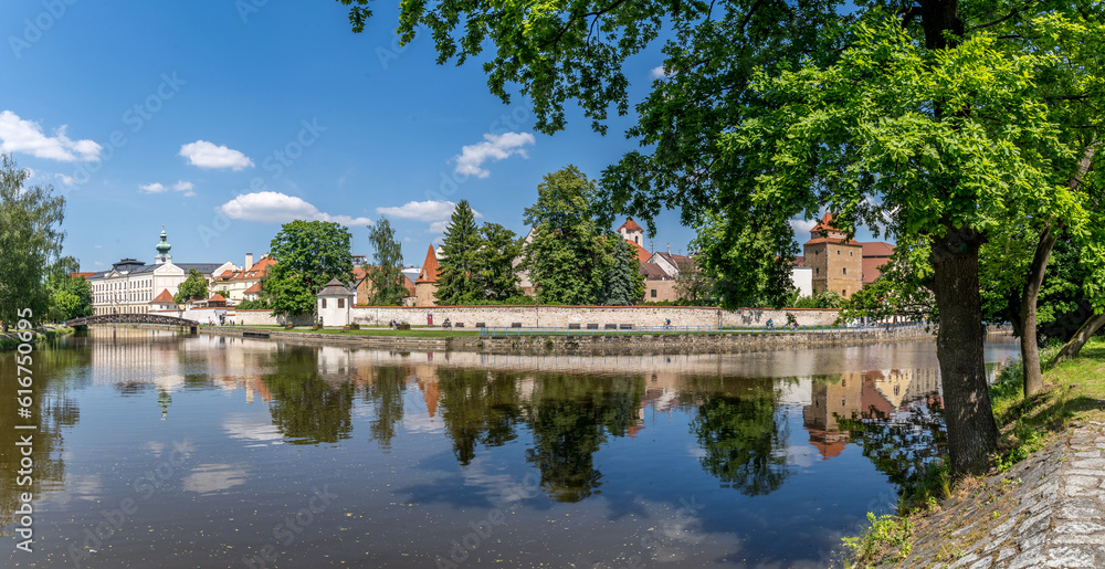 Ceske Budejovice medieval walls reflecting off the Vltava river with blue sky