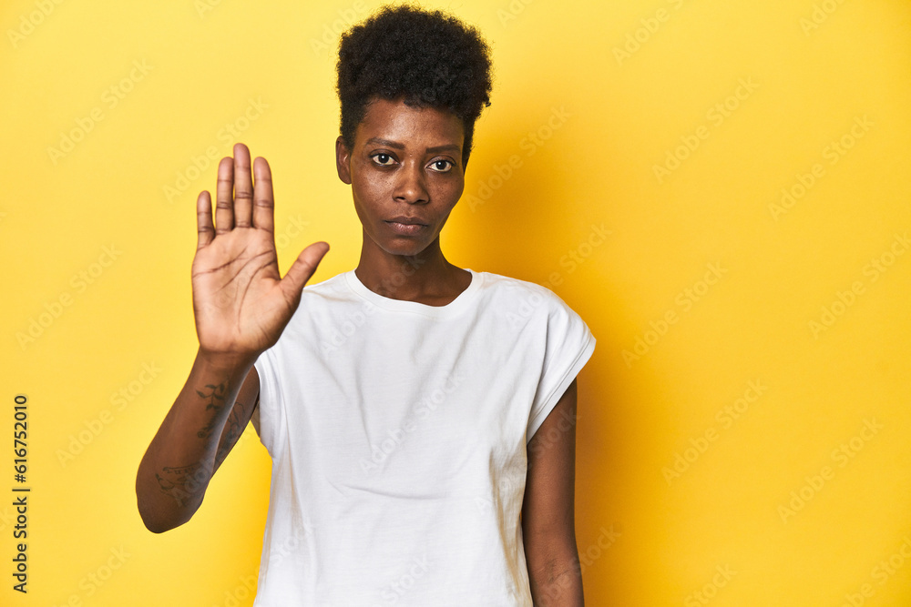 Elegant African woman, short hair, white tank top, Elegant African woman, short hair, white tank topstanding with outstretched hand showing stop sign, preventing you.