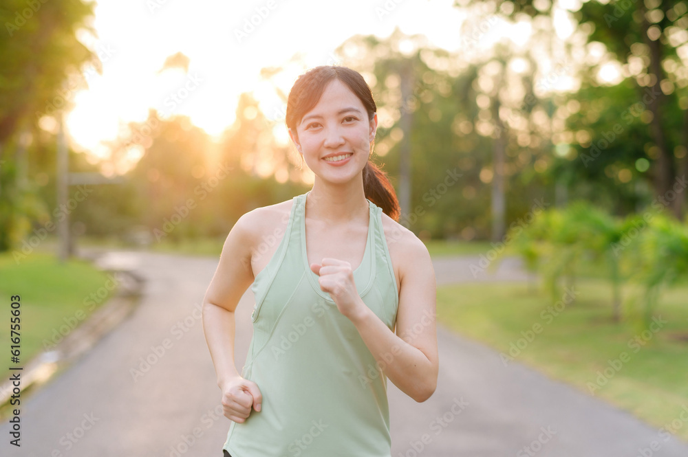 Fit Asian young woman jogging in park smiling happy running and enjoying a healthy outdoor lifestyle. Female jogger. Fitness runner girl in public park. healthy lifestyle and wellness being concept Fit Asian young woman jogging in park smiling happy running and enjoying a healthy outdoor lifestyle. Female jogger. Fitness runner girl in public park. healthy lifestyle and wellness being concept