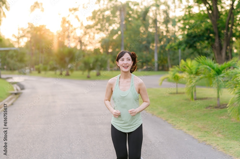 Fit Asian young woman jogging in park smiling happy running and enjoying a healthy outdoor lifestyle. Female jogger. Fitness runner girl in public park. healthy lifestyle and wellness being concept Fit Asian young woman jogging in park smiling happy running and enjoying a healthy outdoor lifestyle. Female jogger. Fitness runner girl in public park. healthy lifestyle and wellness being concept