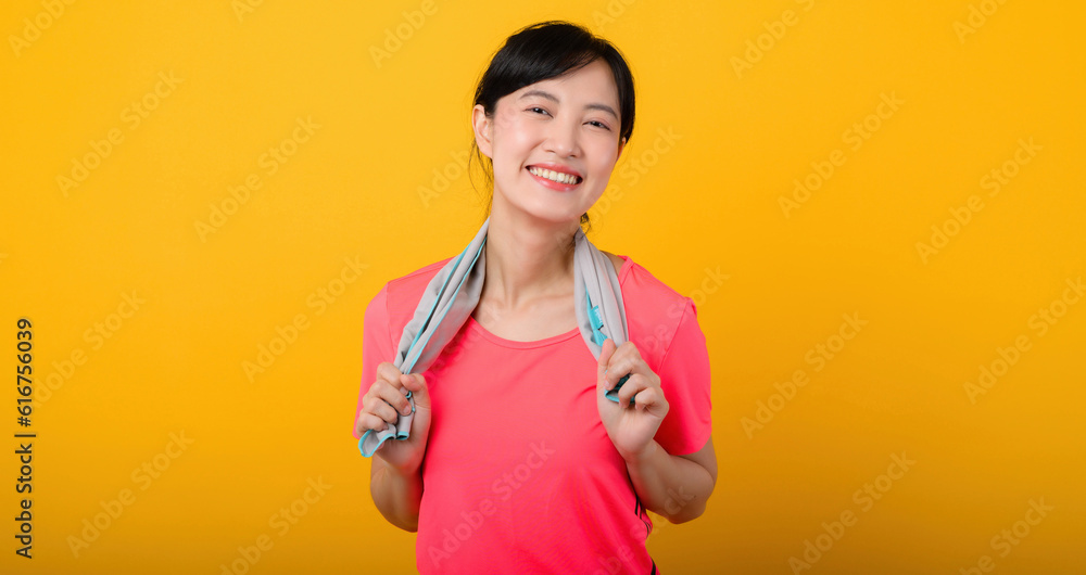 Portrait young asian sports fitness woman happy smile wearing pink sportswear and face towel doing exercise training workout against yellow studio background. wellbeing and healthy lifestyle concept. Portrait young asian sports fitness woman happy smile wearing pink sportswear and face towel doing exercise training workout against yellow studio background. wellbeing and healthy lifestyle concept.