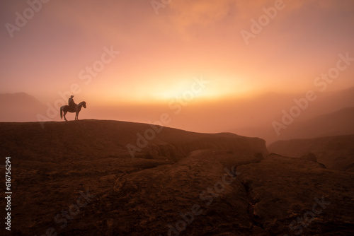 Beautiful sunrise scenery with silhouette horseman and his horse at Bromo Mountain  Bromo Tengger National Park