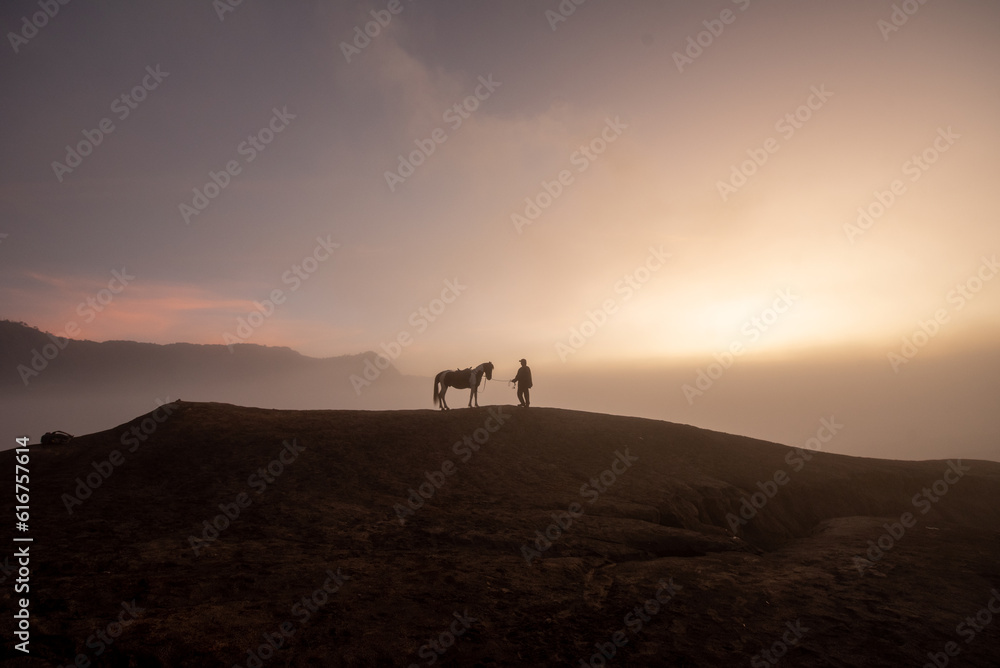 Beautiful sunrise scenery with silhouette horseman and his horse at Bromo Mountain, Bromo Tengger National Park