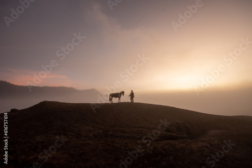 Beautiful sunrise scenery with silhouette horseman and his horse at Bromo Mountain  Bromo Tengger National Park