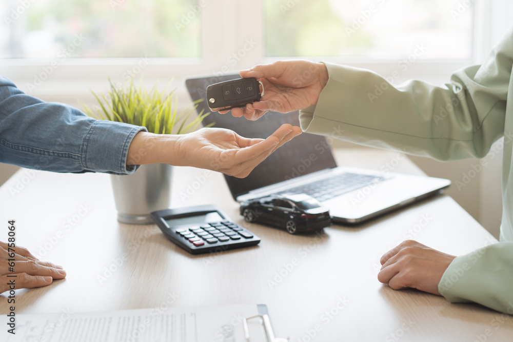 Fototapeta premium Business car rental, sell service, dealership hand of agent dealer, sell asian young woman giving auto key of vehicle to customer renter, female buyer receiving, client or tenant, transfer automobile.