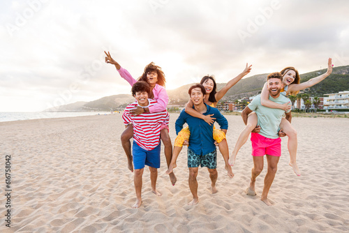 Group of young best friends bonding outdoors - Multiracial happy people having party at the beach during summertime