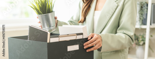 Unemployed, quite job. Desperate asian young businesswoman resigning from company, hand holding cardboard, packing belongings, stuff into box, layoff or changing work. Resignation, employment concept. photo