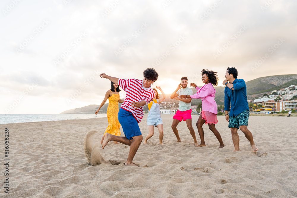Group of young best friends bonding outdoors - Multiracial happy people having party at the beach during summertime