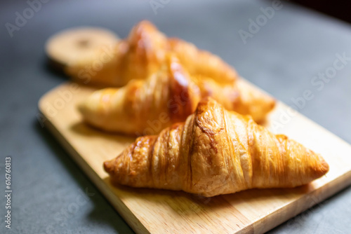Fresh croissant on wooden board with nature sunlight through window.
