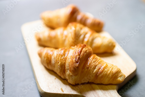 Fresh croissant on wooden board with nature sunlight through window.
