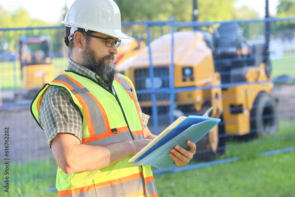 Obraz premium Outdoor builder portrait, construction man worker standing with blueprints