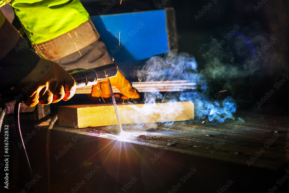 Welder is welding with shielded metal arc welding process to steel