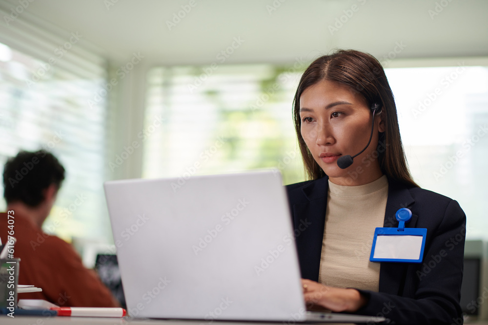 Portrait of elegant entrepreneur wearing headset when working on laptop in office Portrait of elegant entrepreneur wearing headset when working on laptop in office